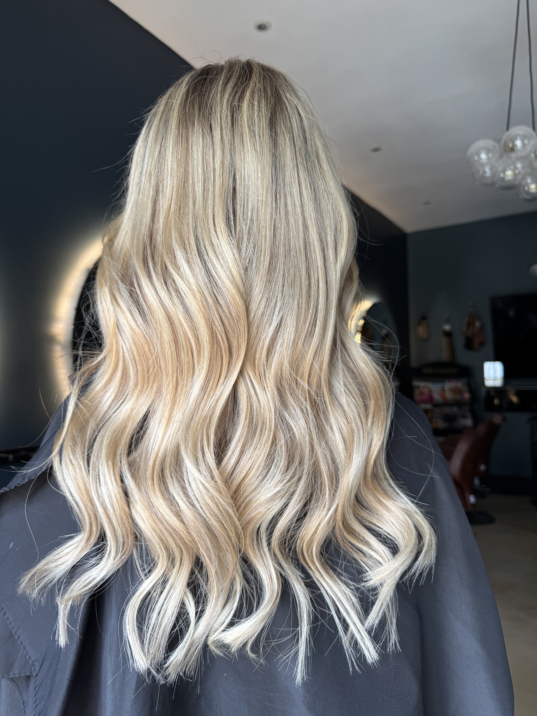 Soft blonde waves styled by Hailey, photographed from behind in the salon